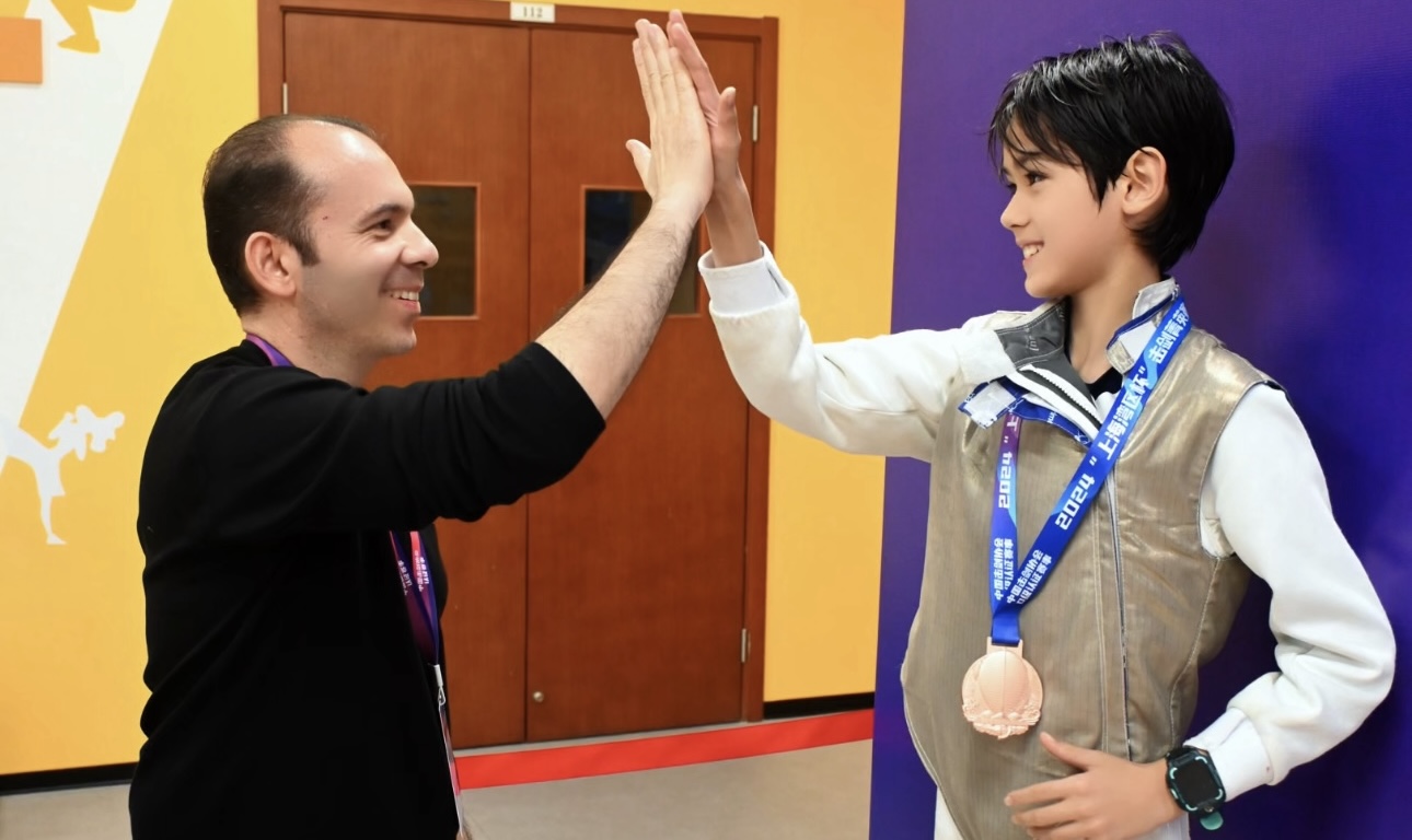 Coach Yousef Alaghehband celebrating with a young fencing medalist
